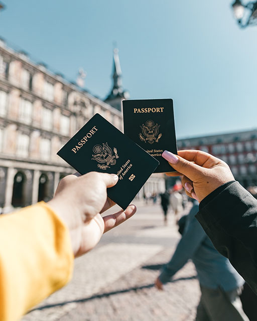 two hands holding passports.  The background is blurred